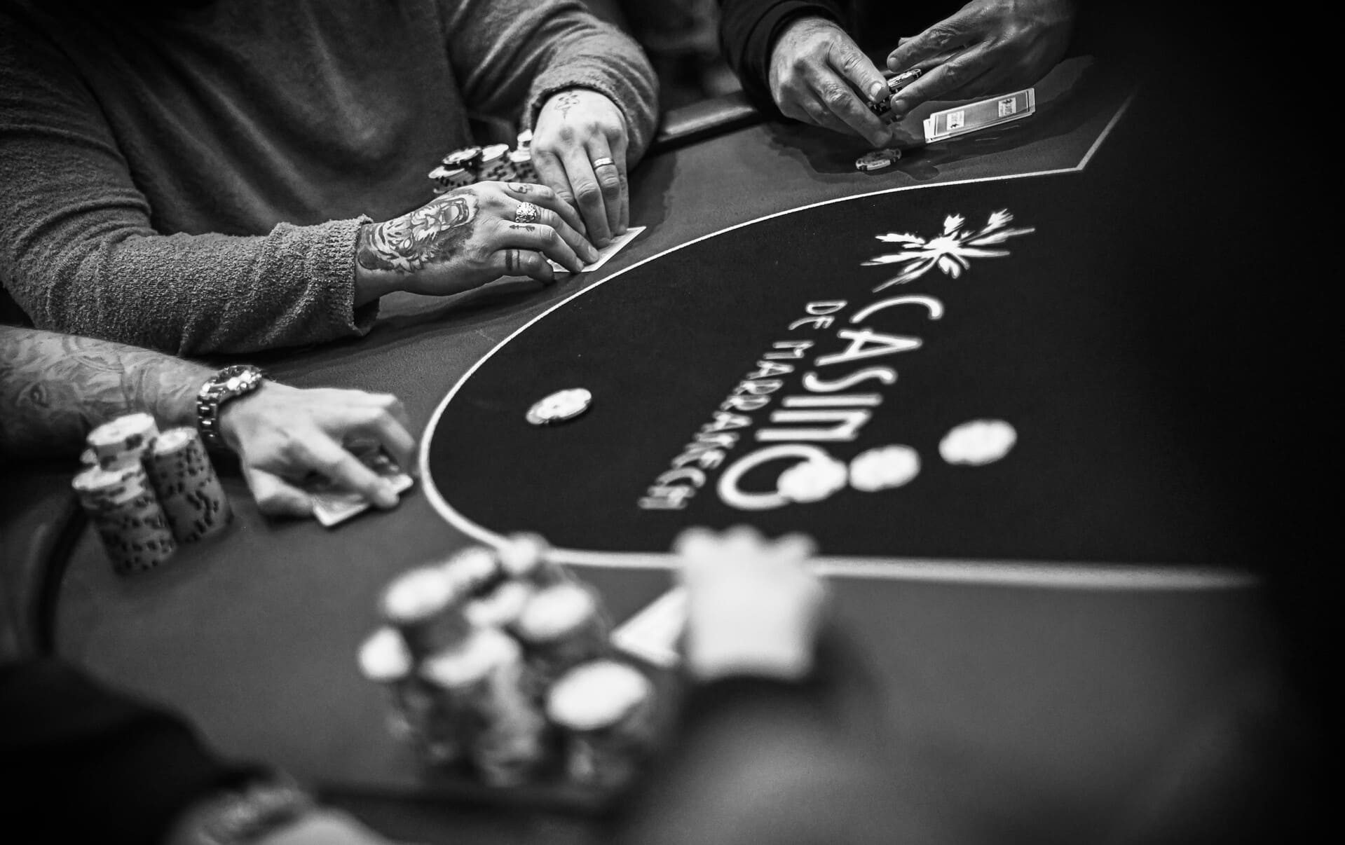 Close-up of players’ hands holding cards and poker chips at a casino blackjack table