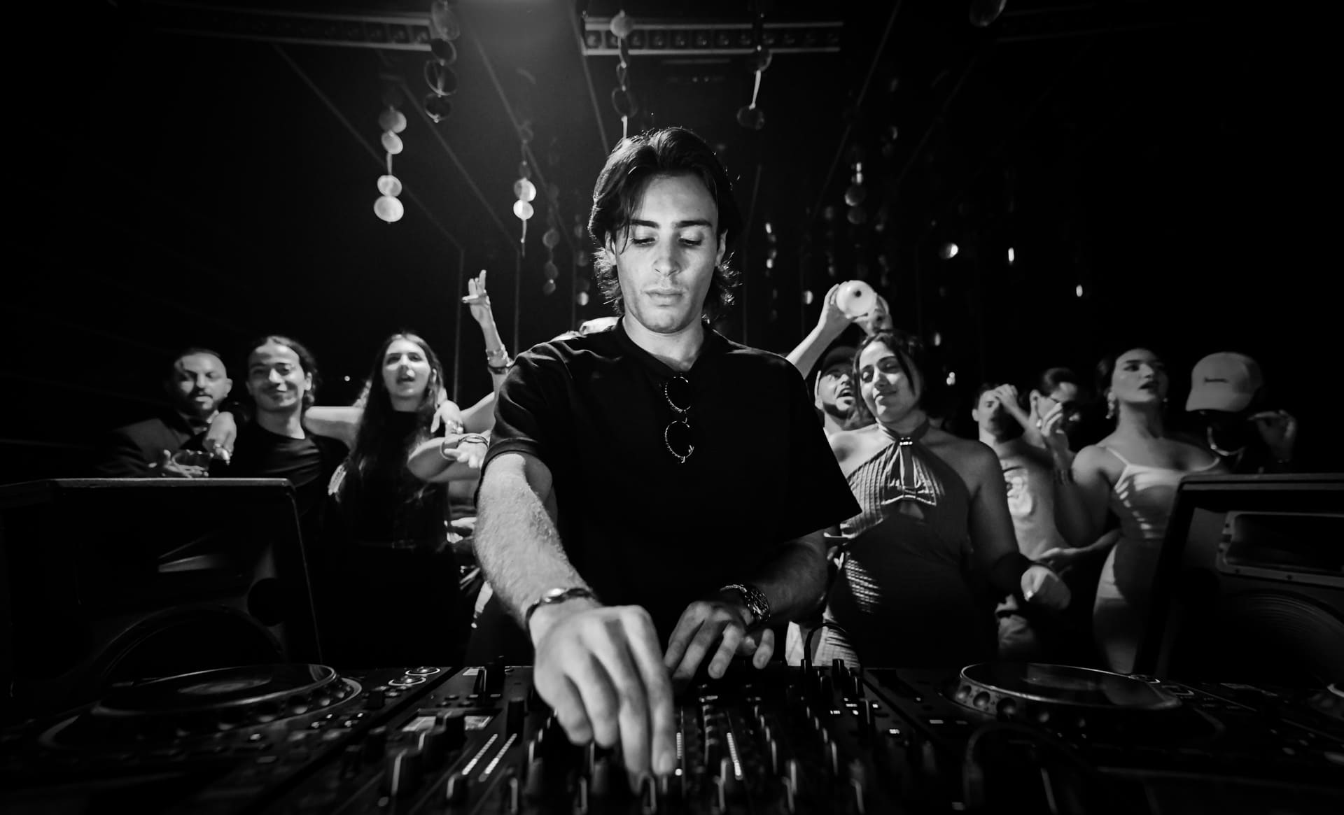 DJ mixing music as crowd dances behind the booth