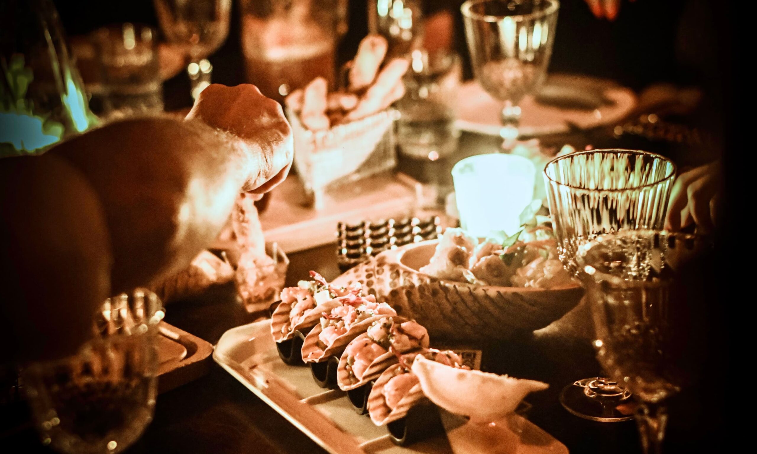 Guests sharing sushi and appetizers at a candlelit dining table