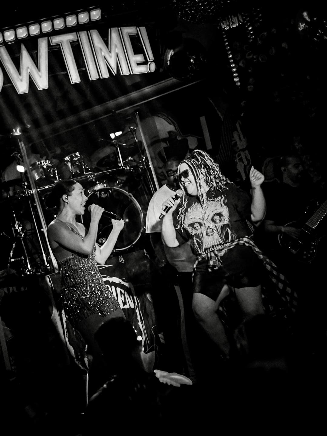 Two vocalists performing together on a nightclub stage during a live show