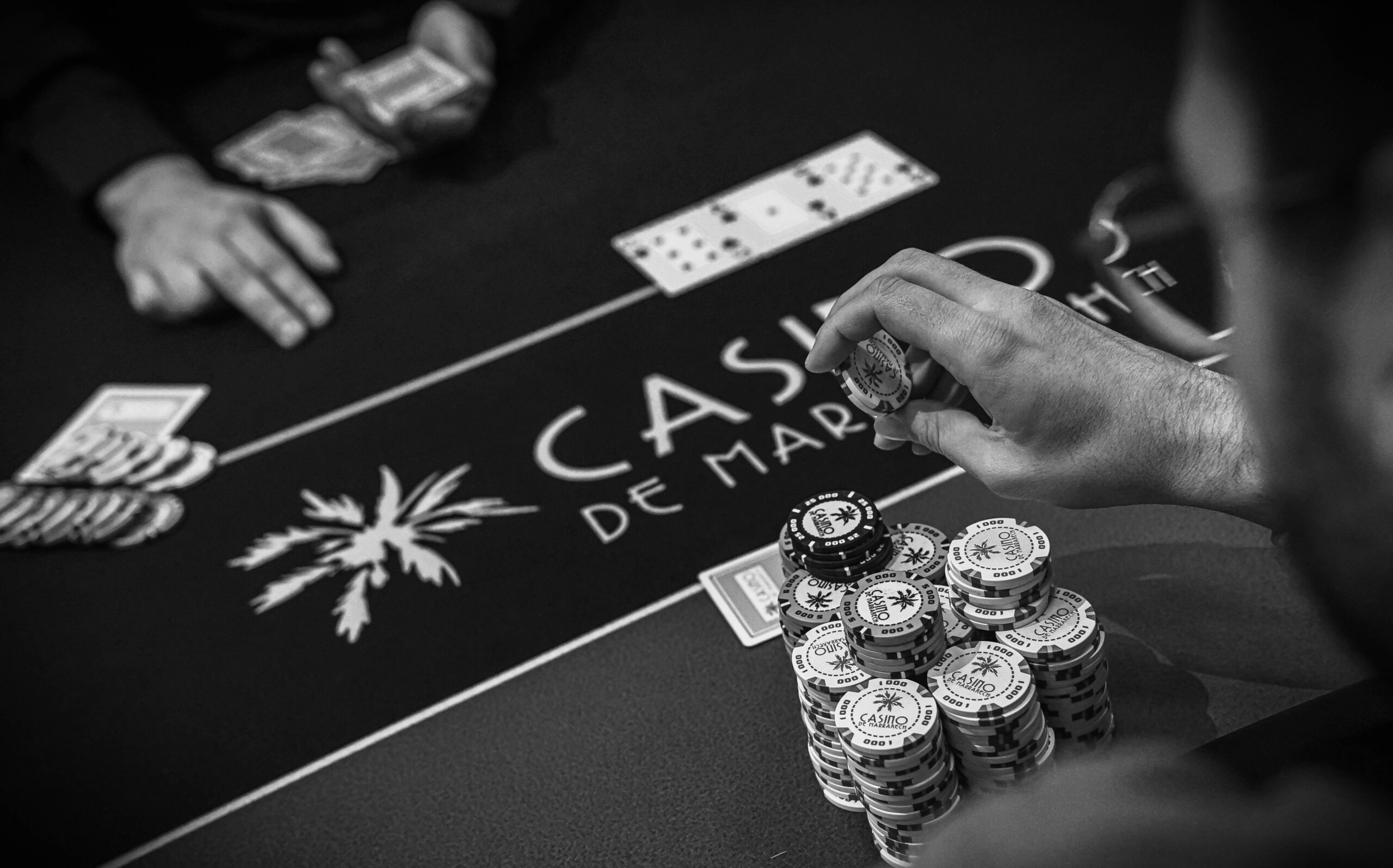 Close-up of players’ hands holding cards and poker chips at a casino blackjack table